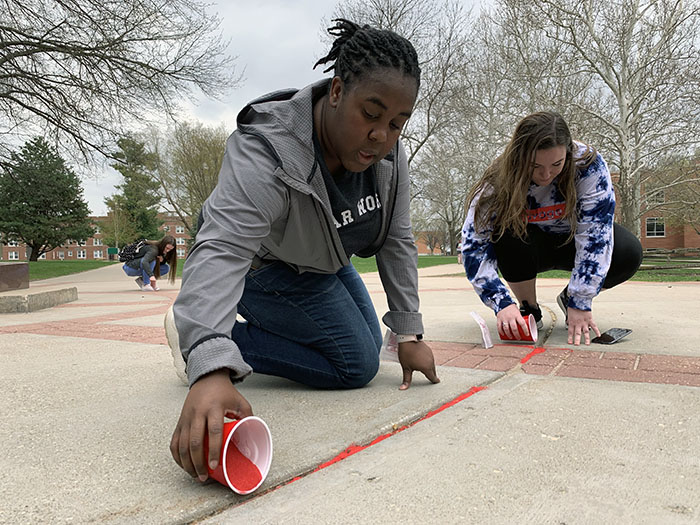 Students poured red sand into the cracks of campus sidewalks Wednesday to raise awareness about human trafficking. 