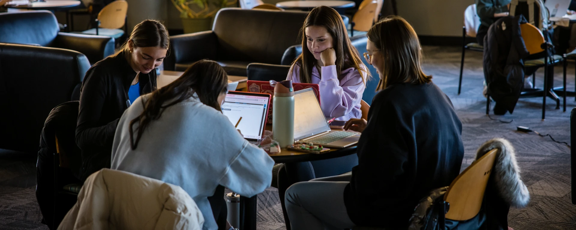 A group of students are seated at a table in the Northwest library