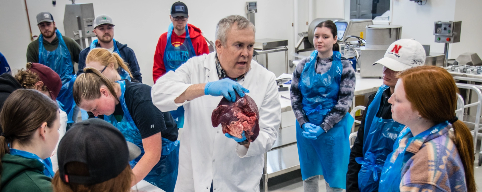 The ag teacher holds a piece of meat so students of the meat science class can evaluate muscle structure and composition.