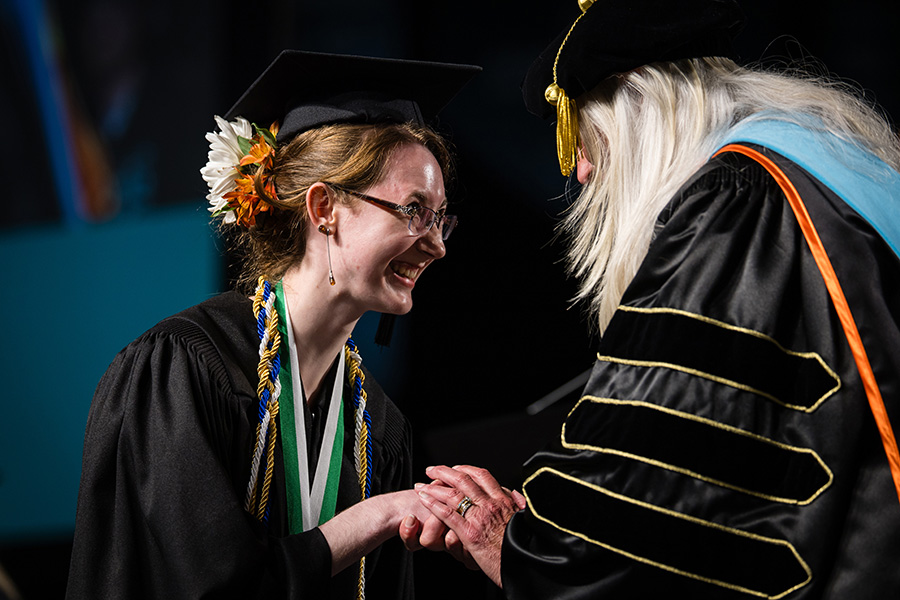 Kiersten Buck, shaking the hand of Northwest Provost Dr. Jamie Hooyman during a commencement ceremony in May, graduated with Bachelor of Science degrees in chemistry: medicinal chemistry, nanoscience: nanoscale biology and nanoscience: nanoscale chemistry. (Photo by Lilly Cook/Northwest Missouri State University) 