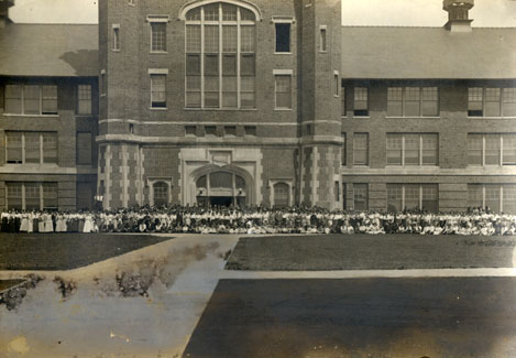 Students, along with faculty and staff, gather outside the front entrance of the Administration Building, known as Academic Hall, for a group photo.