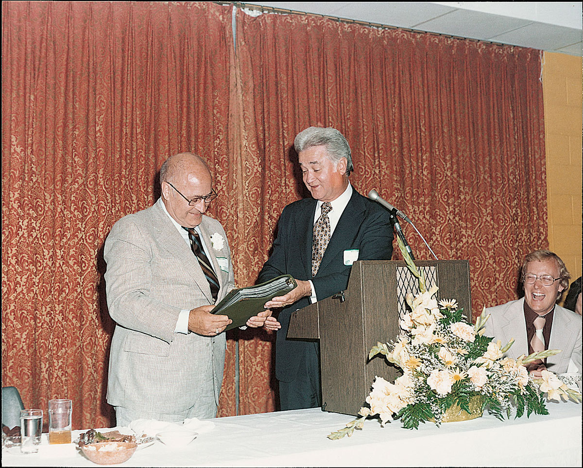 President Foster gives Everett Brown a notebook of letters from friends and colleagues at a retirement dinner in 1976.