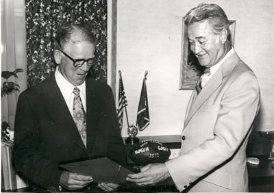 Dr. Robert Foster honors Coach Ryland Milner with an award. Milner became head coach of the Northwest football team in 1932.