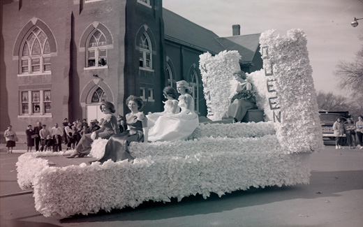 The Northwest Tower Queen, attired in her evening finery, rides on a float with her royal court during the 1962 Homecoming Parade.