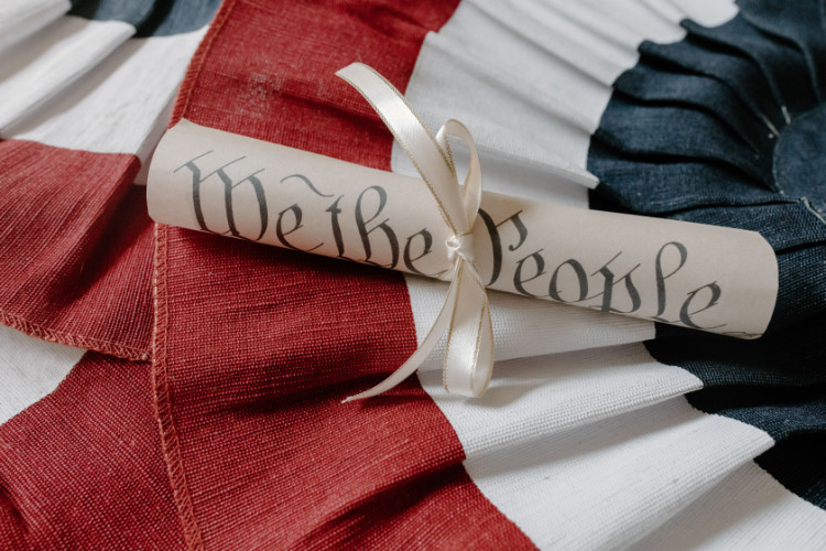 Paper scroll with the words "We the People" sitting on a red, white and blue flag