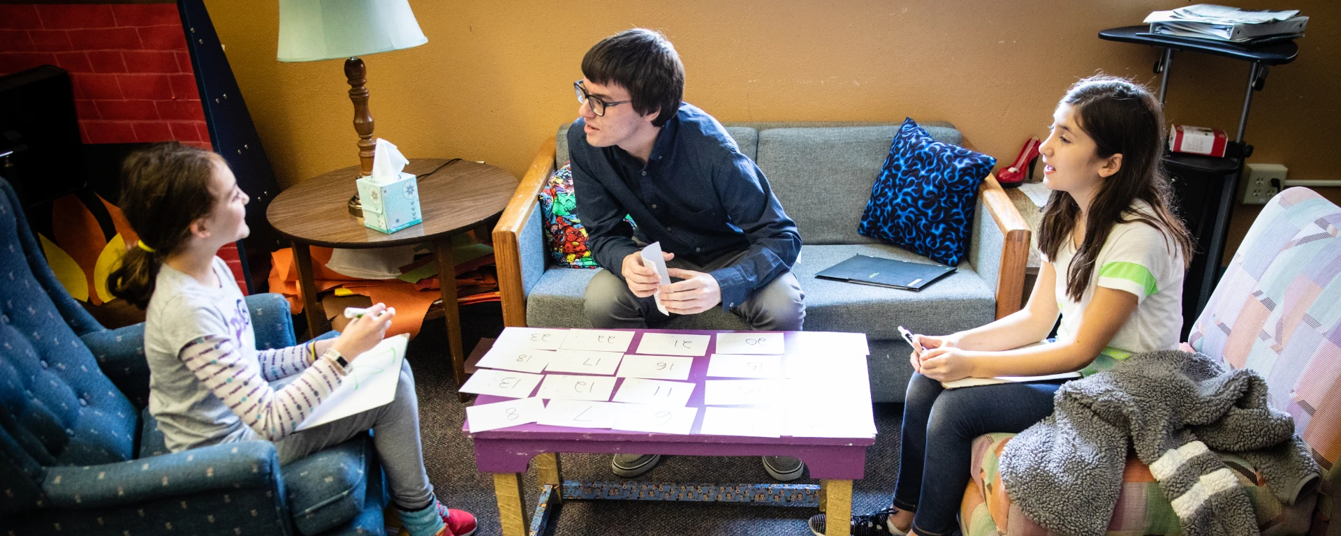 A male Horace Mann student teacher helps two elementary students learn by using flash cards. 
