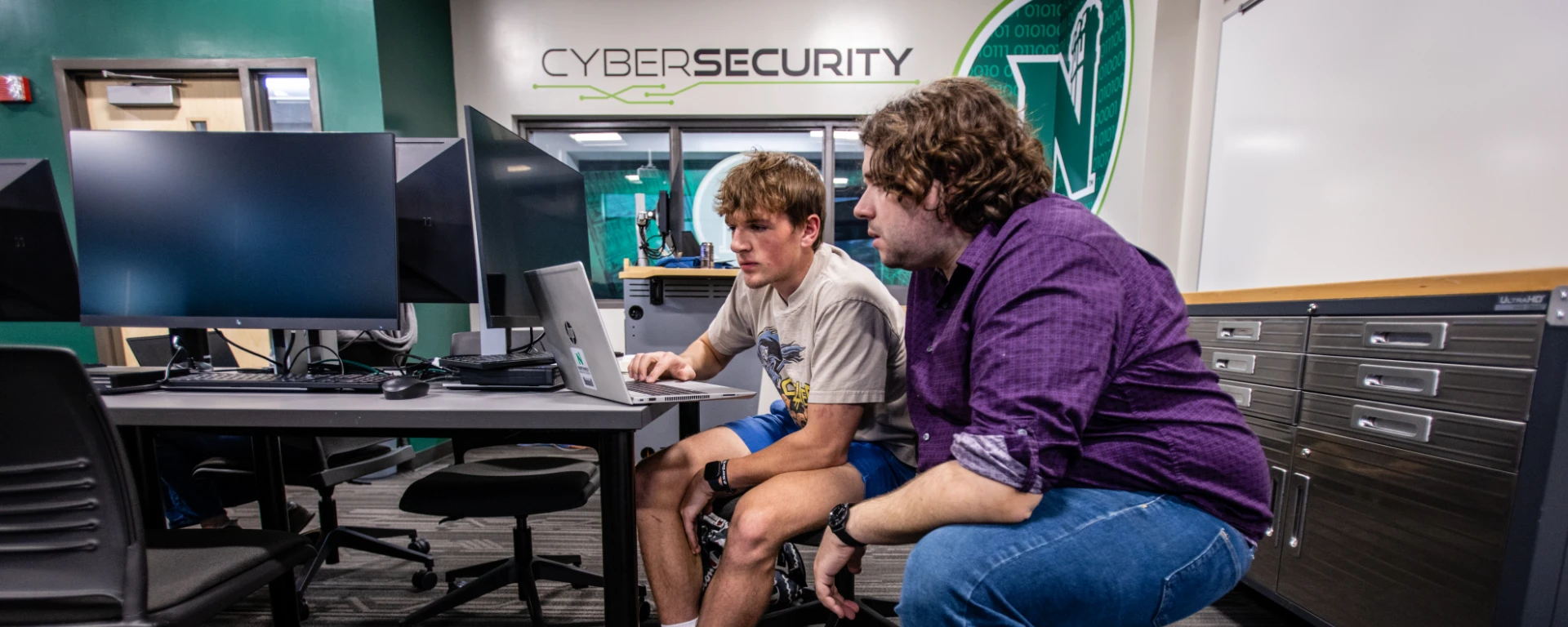 A faculty member helps a student in the recently built cybersecurity lab with modern servers, computers and network devices. 