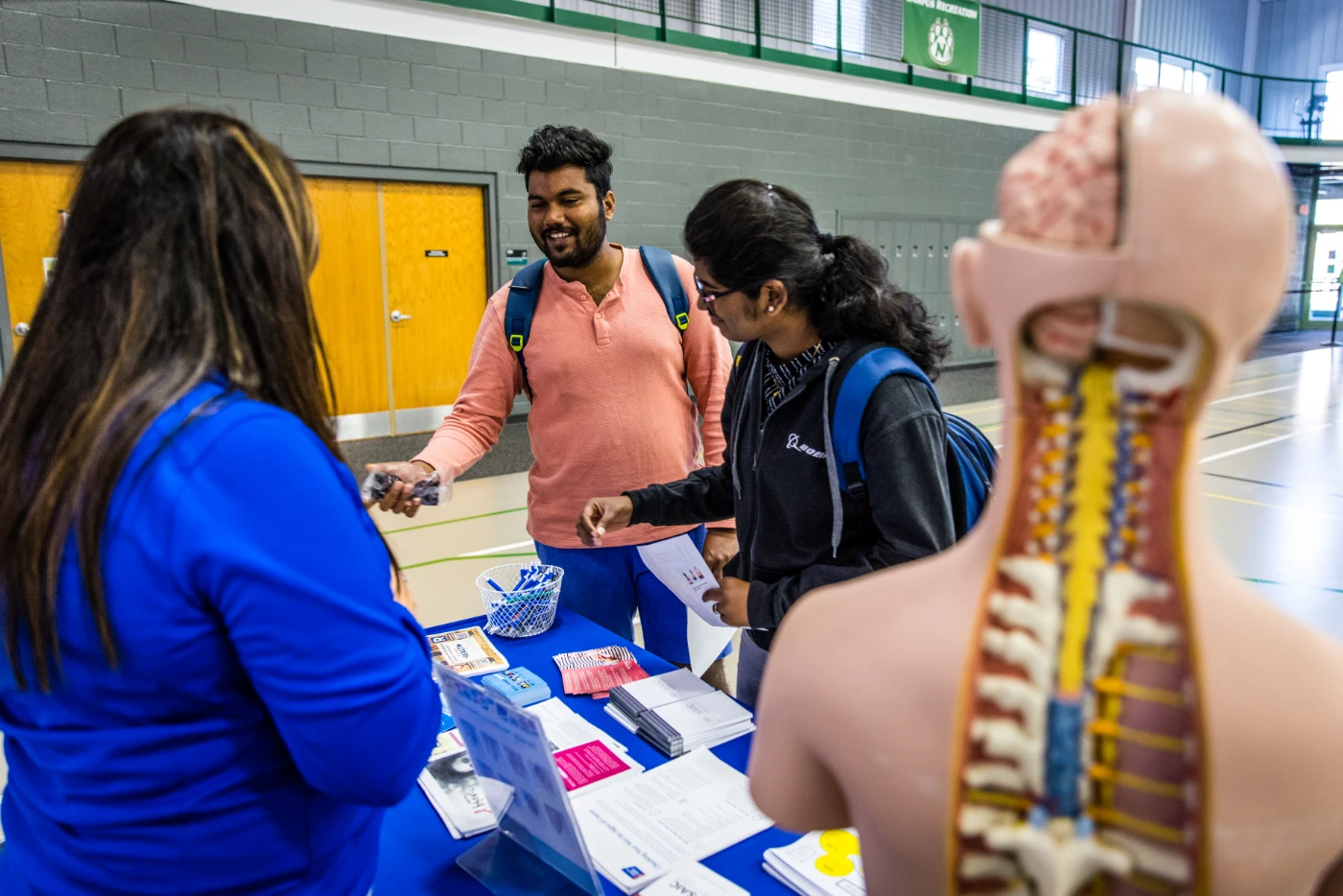 Two students talk to a public health educator at an informational table during the Wellness Fair. 