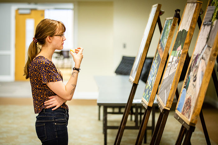 A Northwest student views a series of paintings presented during the annual Celebration of Quality on April 5. (Photo by Brandon Bland/Northwest Missouri State University)