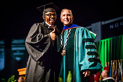 A graduate poses with Northwest President Dr. John Jasinski for a photo after crossing the commencement stage.
