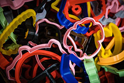 A container holds plastic cookie cutters of multiple colors. The business began making the plastic shapes with 3-D printing technology a few years ago after the Hughes noticed a drop in their sales as competitors began offering plastic shapes.