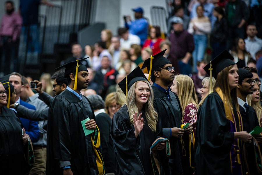 A graduate waves to a loved one in the crowd gathered to view Friday's commencement ceremonies at Northwest.