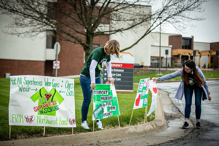 Brooke McAtee (left), the director of nursing at Northwest, and Darci Wray, a secretary for the nursing program, on Monday placed signs of support for local healthcare professionals along the entry road to Mosaic Medical Center in Maryville. (Photo by Todd Weddle/Northwest Missouri State University) 