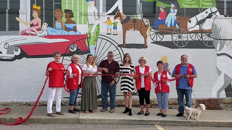 Sierra Scott (third from left) and Shelby Theis (fifth from left) joined community members in Oregon, Missouri, last month to cut a ribbon in celebration of a mural the Northwest art students completed on a downtown building. (Submitted photos)