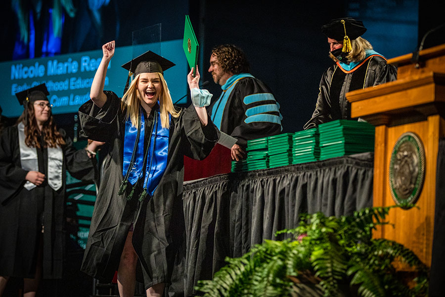 A Northwest graduate celebrates the completion of her degree as she crosses the stage during one of Northwest's spring commencement ceremonies Friday. (Photo by Todd Weddle/Northwest Missouri State University)