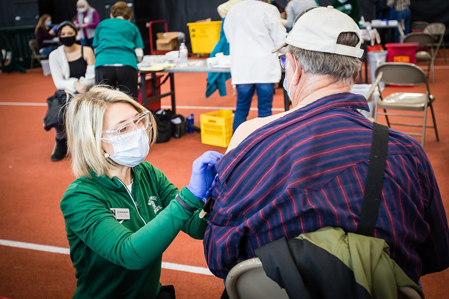 Dr. Brooke McAtee, the director of Northwest's nursing program, gives the COVID-19 vaccination to a community member during a vaccination clinic last spring at the Carl and Cheryl Hughes Fieldhouse. Northwest is offering prizes to Northwest students are fully vaccinated as the fall semester begins. (Photo by Todd Weddle/Northwest Missouri State University)