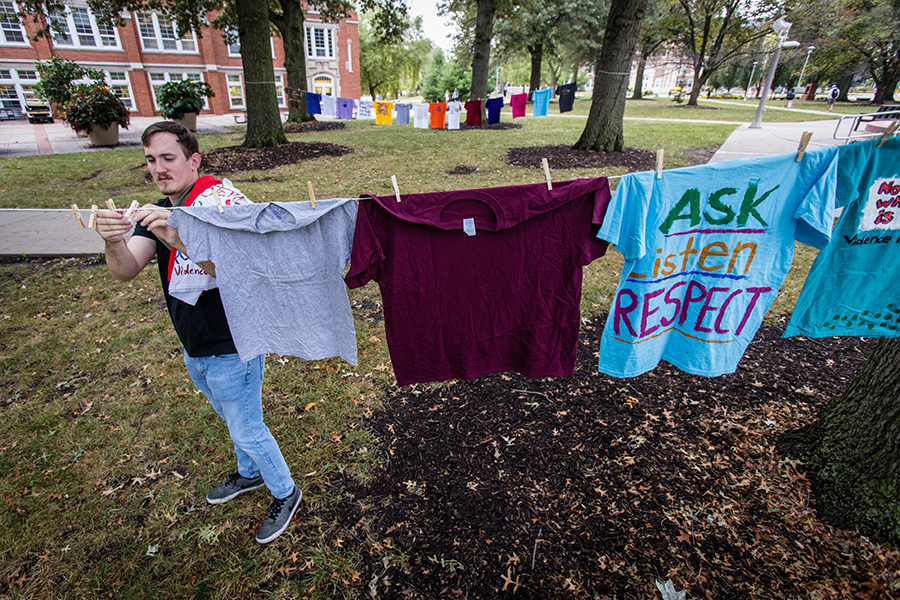 Northwest’s Green Dot coordinator Benjamin Moran hangs shirts comprising the Clothesline Project at the base of the Memorial Bell Tower Friday. The display, which raises awareness for violence prevention, will continue through Oct. 15. (Photo by Todd Weddle/Northwest Missouri State University)