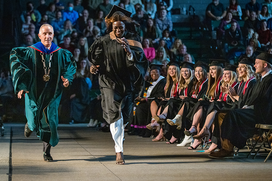 President Jasinski races Hiba Mahgoub in front of the commencement stage.