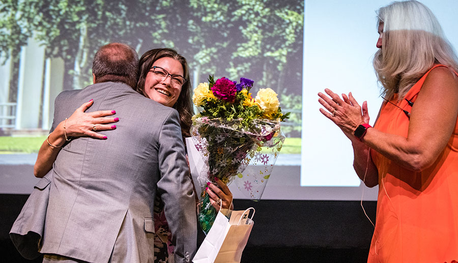 Dr. Nissa Ingraham receives a hug from Associate Provost Dr. Mike Steiner and Provost Dr. Jamie Hooyman applauds after Ingraham was announced Friday as Northwest's 2023 Governor’s Award for Excellence in Education recipient. (Photo by Lauren Adams/Northwest Missouri State University)