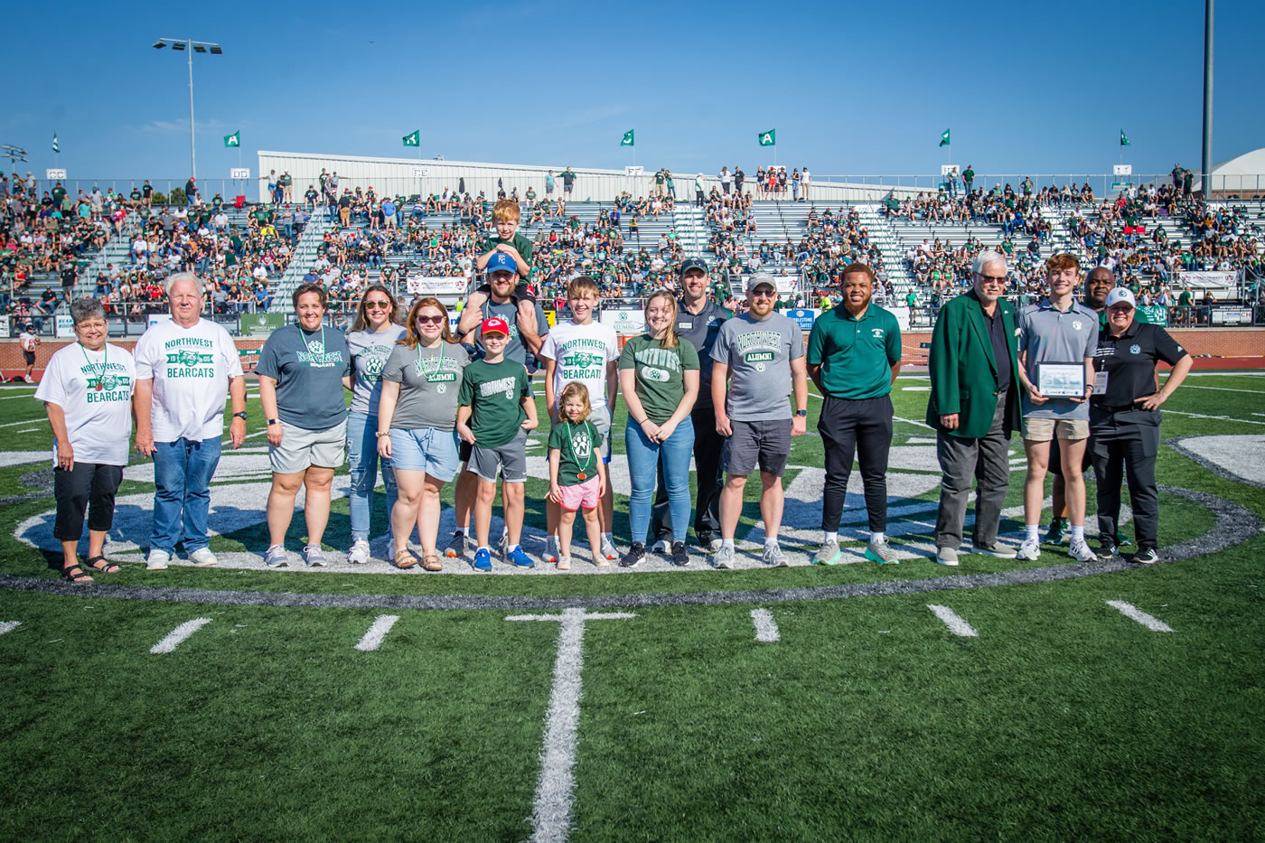 The Swink family was honored during Saturday’s Bearcat football game as the Northwest Family of the Year. Left to right are Sherry Swink; Arnold Swink; Jennifer Swink; Abby Swink; Kara Petrovic; John Petrovic, holding Charlie and with Jack standing in front of him; Aiden Petrovic with Lucy Petrovic standing in front of him; Anna Swink; Director of Alumni Relations Duane Havard; Brian Swink; Student Senate Executive Vice President Dami Popoola; Northwest President Emeritus Dr. Dean Hubbard; Henry Swink; Northwest Interim President Dr. Clarence Green; and Interim Director of Campus Dining Sara Tompkins.