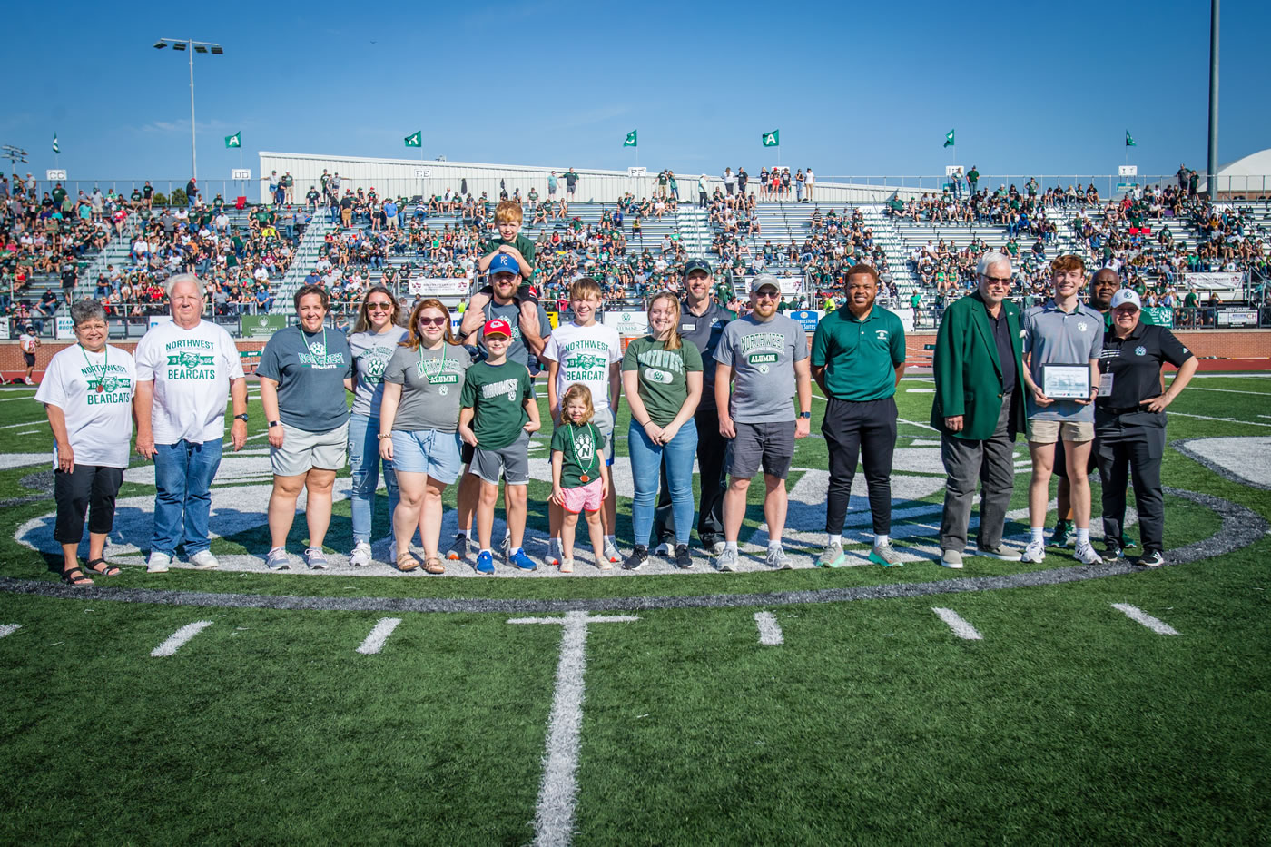 The Swink family was honored as the 2022 Northwest Family of the Year. Left to right are Sherry Swink; Arnold Swink; Jennifer Swink; Abby Swink; Kara Petrovic; John Petrovic, holding Charlie and with Jack standing in front of him; Aiden Petrovic with Lucy Petrovic standing in front of him; Anna Swink; Director of Alumni Relations Duane Havard; Brian Swink; Student Senate Executive Vice President Dami Popoola; Northwest President Emeritus Dr. Dean Hubbard; Henry Swink; Northwest Interim President Dr. Clarence Green; and Interim Director of Campus Dining Sara Tompkins.