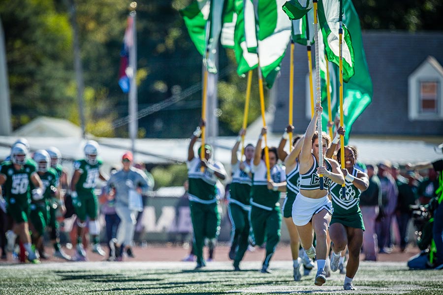 Bearcat cheerleaders run flags onto the Bearcat Stadium field during last year's Homecoming football game. (Photo by Todd Weddle/Northwest Missouri State University)
