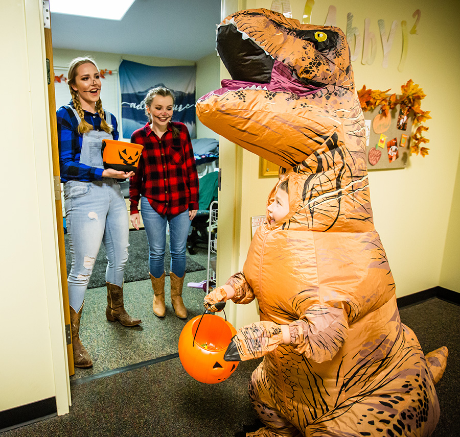 A pair of Northwest students greet a trick-or-treater at the door of their residence hall room during a trick-or-treating event. Area families are invited to Northwest residence halls for trick-or-treating from 5 to 7 p.m. Oct. 26. (Northwest Missouri State University photo)  