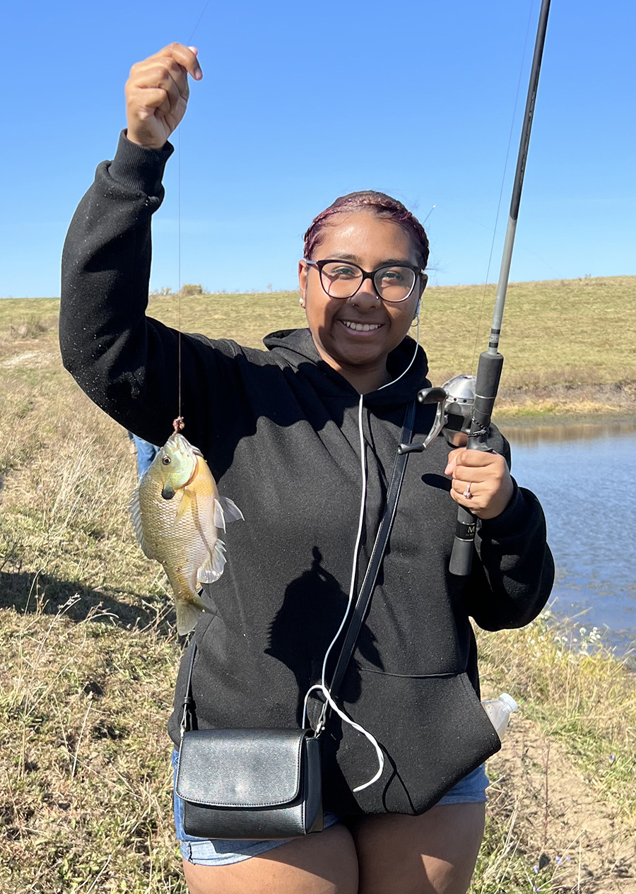 Aisah Domitilia Barandica shows a fish she caught during a tour of a local farm this fall with the Friends of International Students. (Submitted photo)