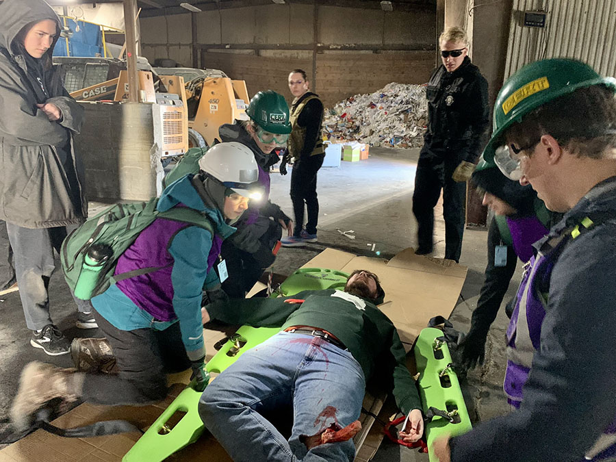 First responders assess an earthquake victim's injuries during the Atlantic Hope disaster simulation while members of the Atlantica MNS extremist group watch over them.