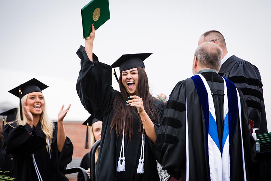 A graduating student celebrates the conferral of her degree as she crosses Northwest's commencement stage.