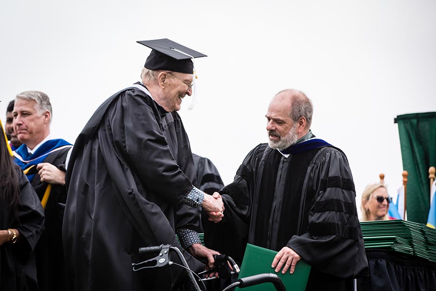 Dr. Mike Steiner, associate provost of undergraduate studies and dean of the College of Arts and Sciences, congratulated Gordon Hill as he crossed the commencement stage at Bearcat Stadium. 