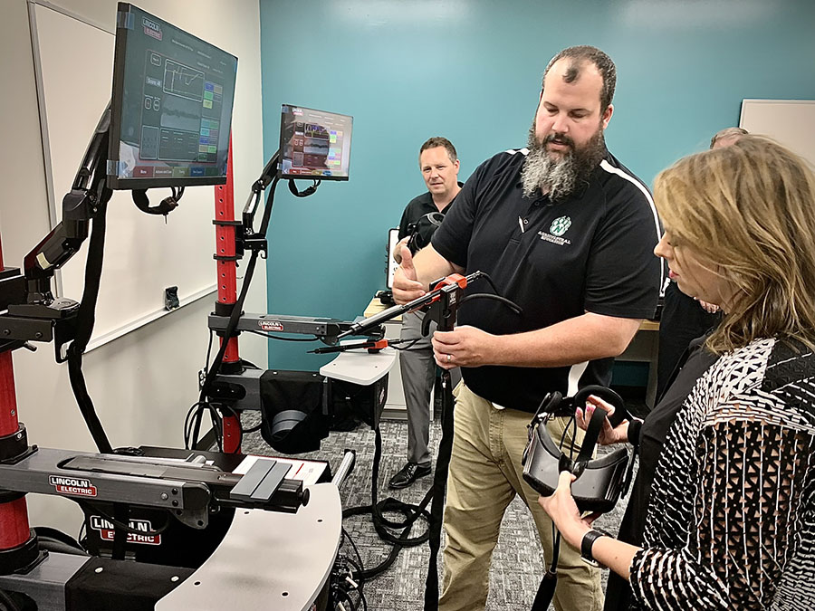 Matthew Bax, an agricultural sciences instructor at Northwest, demonstrates how to use a welding simulator in the remodeled McKemy Center with Shad Burner, director of federal initiatives with the Missouri Dept. of Economic Development, and Michelle Hataway, acting director of the Missouri Dept. of Economic Development. 