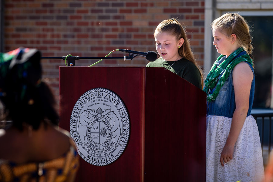 Horace Mann students Karina Wall and Raeley Kirkpatrick presented the flag their class designed during Northwest's flag-raising ceremony. (Photo by Lauren Adams/Northwest Missouri State University)