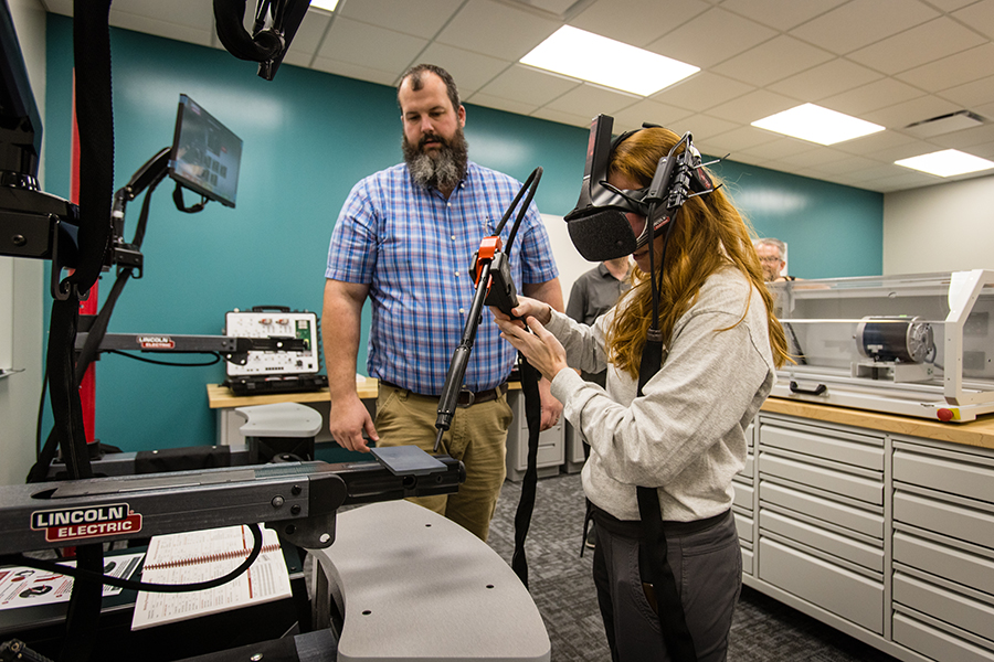 Matt Bax, an instructor of agricultural Sciences, assists a student who is using a welding simulator in the remodeled McKemy Center. 