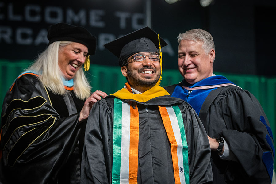 Provost Dr. Jamie Hooyman and Dr. Greg Haddock, associate provost of graduate studies and special programs, place a master's degree hood on a Northwest graduate.