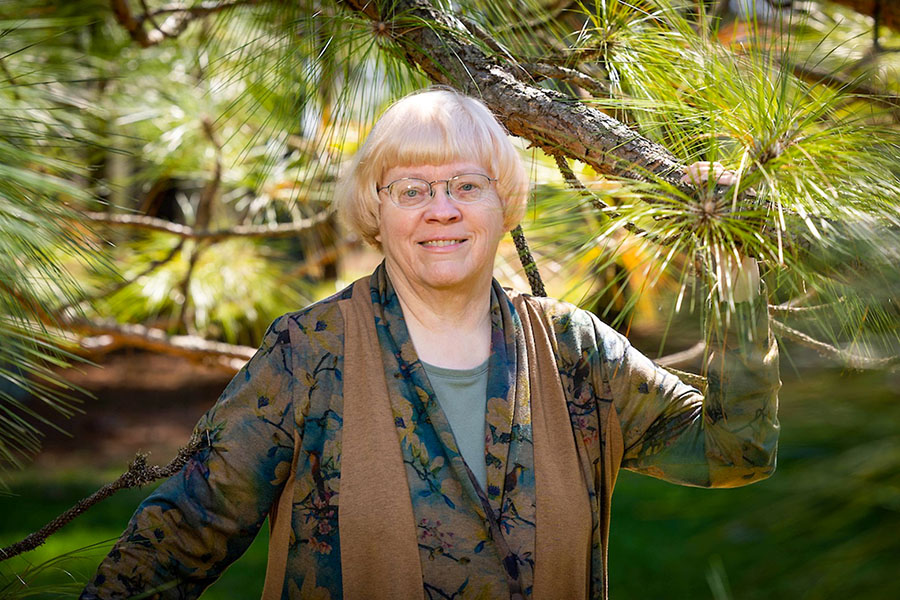 Dr. Carol Miller stands with a longleaf pine last summer at Lovett Pinetum in Strafford, Missouri. During her 40 years of teaching, Miller has taken a special interest in environmental law. (Photo by Kevin White / Missouri State University)