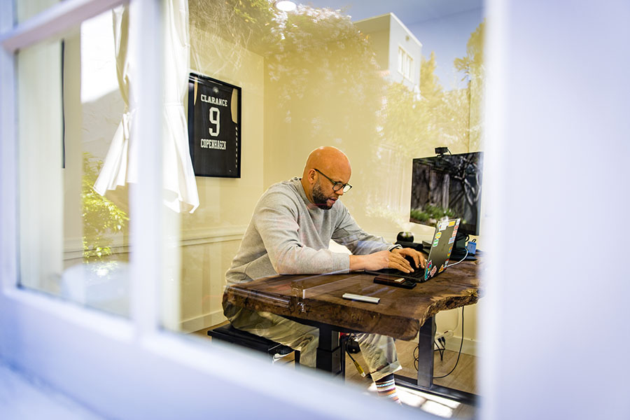 Bilal Clarance spends time working in his home office, where jerseys from his playing days in Denmark hang on the wall.