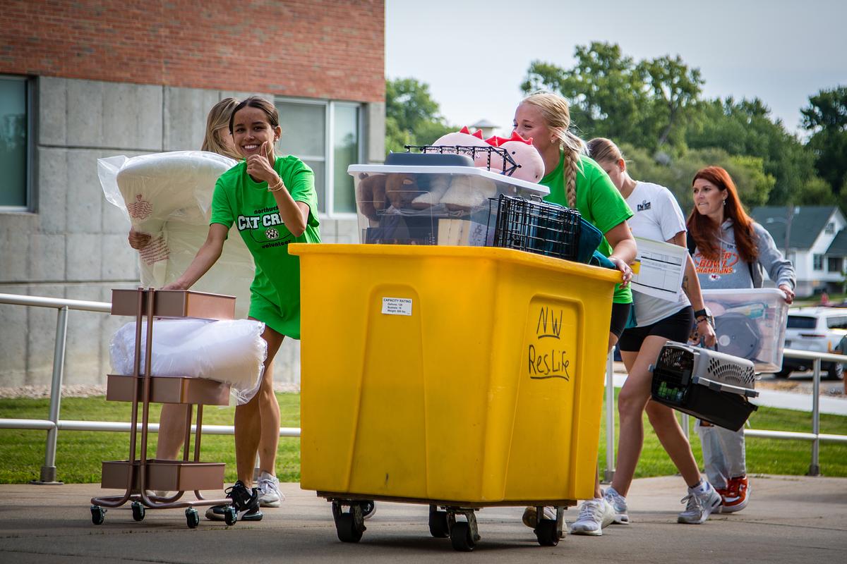 Members of the Cat Crew are seen pushing a yellow cart on Move-in day