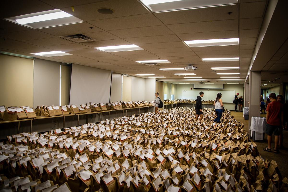 Hundreds of brown paper bags with books inside cover the floor at textbook pickup