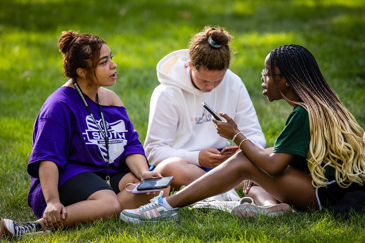 A group of students sit on the lawn during New Student Celebration