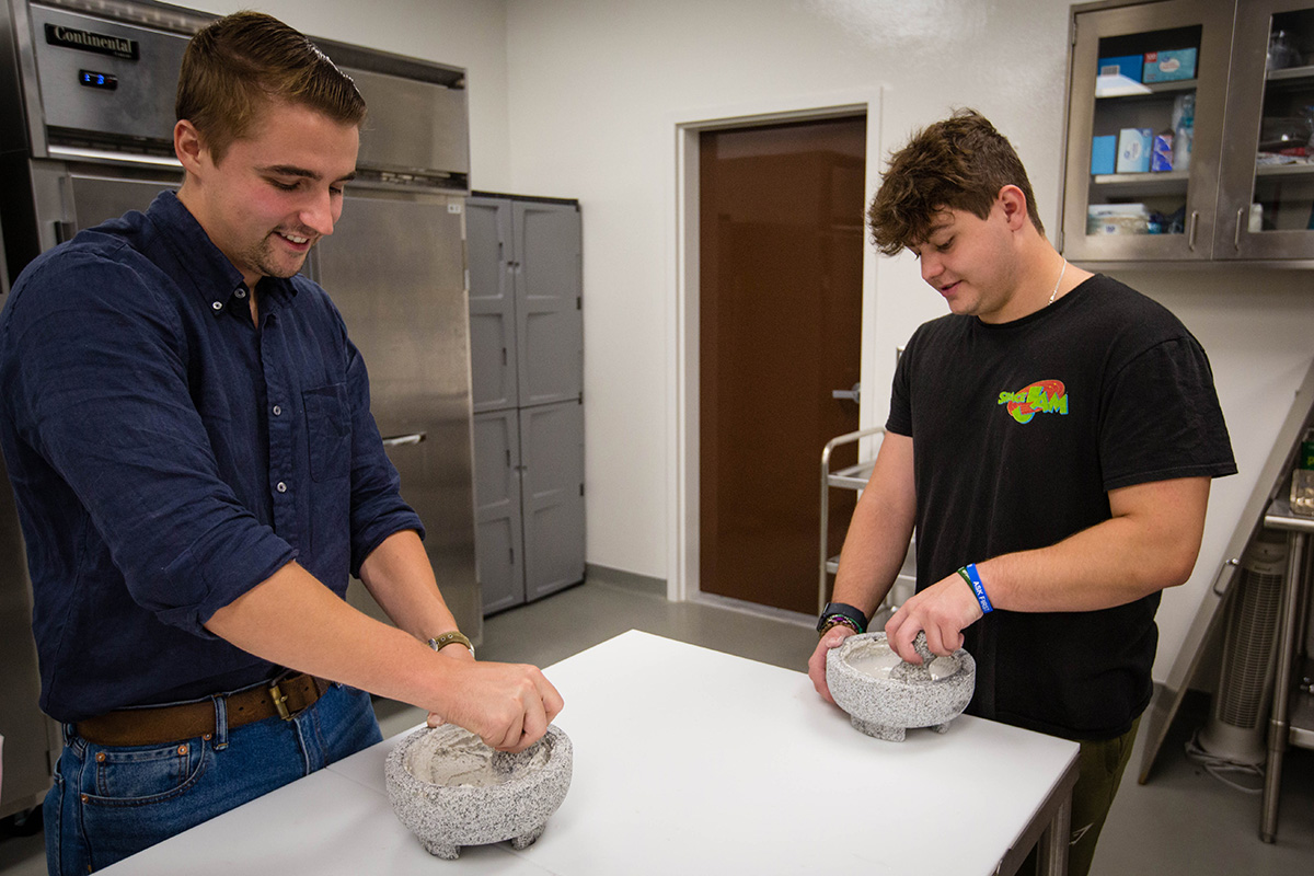 Assistant Professor of Agricultural Sciences Dr. Jake Tuell, left, assists a student with food preparation in a world foods course at Northwest's Agricultural Learning Center. (Photo by Abigayle Rush/Northwest Missouri State University)