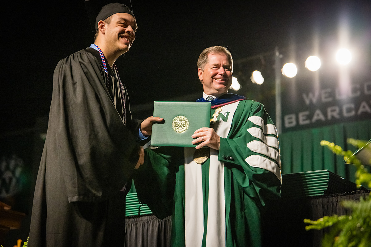 A Northwest student stands for a photo with Dr. Lance Tatum, the University's president, while crossing the commencement stage. (Photo by Todd Weddle/Northwest Missouri State University)