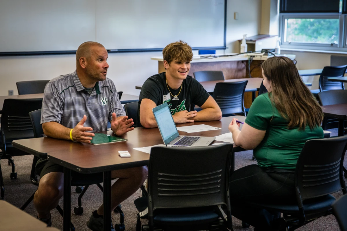 A student and a parent meet with their advisor to discuss class schedules.